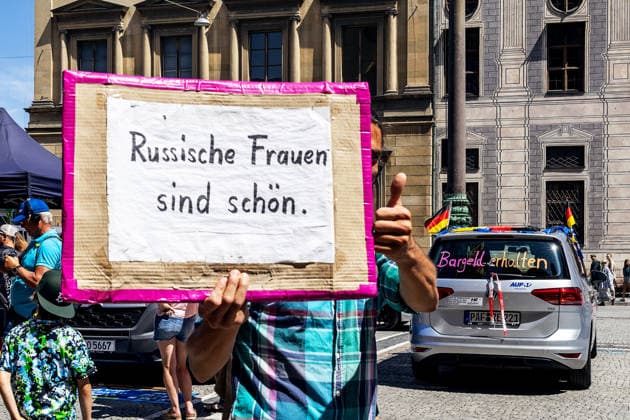 Munich, Bavaria, Germany - July 25, 2026: Protesters demonstrate in downtown Munich against Chancellor Friedrich Merz (CDU) and the federal government s policies. The rally is directed, among other things, against the government s economic and social policies. A man holds a sign that reads: RUSSIAN WOMEN ARE BEAUTIFUL *** Teilnehmer demonstrieren in der Münchner Innenstadt gegen Bundeskanzler Friedrich Merz (CDU) und die Politik der Bundesregierung. Die Kundgebung richtet sich unter anderem gegen die Regierungs- und Sozialpolitik. Ein Mann hält ein Plakat mit Aufschrift: RUSSISCHE FRAUEN SIND SCHÖN