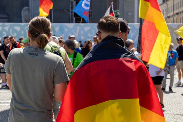 Munich, Bavaria, Germany July 25, 2026: Protesters demonstrate in downtown Munich against Chancellor Friedrich Merz (CDU) and the federal government™s policies. The rally is directed, among other things, against the government™s economic and social policies. Protesters carrying German flags *** Teilnehmer demonstrieren in der Münchner Innenstadt gegen Bundeskanzler Friedrich Merz (CDU) und die Politik der Bundesregierung. Die Kundgebung richtet sich unter anderem gegen die Regierungs- und Sozialpolitik. Demonstranten mit Deutschlanfahnen