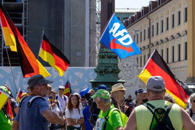 Munich, Bavaria, Germany - July 25, 2026: Protesters demonstrate in downtown Munich against Chancellor Friedrich Merz (CDU) and the federal government s policies. The rally is directed, among other things, against the government s economic and social policies. Protesters carrying German flags and flags of the AfD (Alternative for Germany) party *** Teilnehmer demonstrieren in der Münchner Innenstadt gegen Bundeskanzler Friedrich Merz (CDU) und die Politik der Bundesregierung. Die Kundgebung richtet sich unter anderem gegen die Regierungs- und Sozialpolitik. Demoteilnehmer mit Deutschland Flaggen bzw. Fahnen und Fahnen der Partei AfD (Alternative für Deutschland)