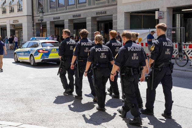 Munich, Bavaria, Germany July 25, 2026: Protesters demonstrate in downtown Munich against Chancellor Friedrich Merz (CDU) and the federal government™s policies. The rally is directed, among other things, against the government™s economic and social policies. Bavarian police are accompanying the march with a patrol car and numerous uniformed officers *** Teilnehmer demonstrieren in der Münchner Innenstadt gegen Bundeskanzler Friedrich Merz (CDU) und die Politik der Bundesregierung. Die Kundgebung richtet sich unter anderem gegen die Regierungs- und Sozialpolitik. Die bayerische Polizei begleitet den Demozug mit einem Streifenwagen und zahlreichen Polizisten in Uniform