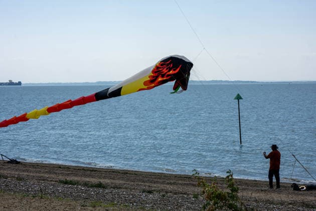 July 25, 2026, Essex, United Kingdom: A giant flame-patterned snake or dragon kite stretches across the sky above the shoreline as a man photographs it from the beach during the Kite Festival at Southend-On-Sea. The Kite Festival Southend s Alternative Airshow, organised by Project Southchurch, was held on the Eastern Esplanade at Thorpe Bay seafront, Southend-On-Sea, Essex. Essex United Kingdom - ZUMAs197 20260725_aaa_s197_431 Copyright: xIanxDavidsonx