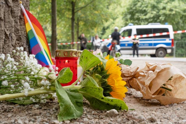 Tatort CSD-Anschlag am Ahornsteig im Tiergarten, Passanten haben zum Gedenken eine Regenbogenfahne, eine Kerze und Sonnenblumen niedergelegt, Trauer um die Opfer, Berlin, 26. Juli 2026 Deutschland, Berlin, 26. Juli 2026, Tatort CSD-Anschlag am Ahornsteig im Tiergarten, Passanten haben 80 Meter vom Tatort eine Regenbogenfahne, ein Grablicht und Sonnenblumen niedergelegt, einen Erinnerungsort geschaffen, ein Polizeifahrzeug riegelt den Bereich ab, dahinter steht noch immer der Citroen Transporter, der hier gestern Abend vor einen Baum krachte, Polizei untersucht Transporter und Anschlagsort, Szene am Sonntagmorgen um 11:45 Uhr, 14 Stunden nach dem Terroranschlag, bei dem ein Mensch starb und weitere teils schwer verletzt wurden, *** Crime Sce