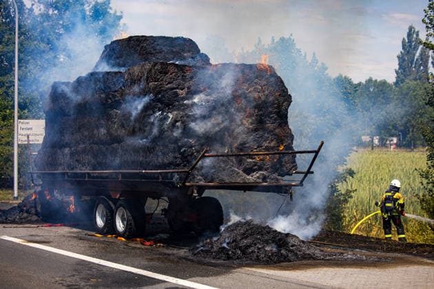 Strohballen fangen auf Anhänger Feuer Landwirt koppelt Traktor ab Flammen greifen auf Vegetation über Am 26.07.2026 geriet auf der L3114 zwischen Groß-Zimmern und Dieburg ein mit Strohquaderballen beladener Anhänger eines Traktors in Brand. Ein Landwirt koppelte nach Hinweisen von Autofahrern den Traktor ab und alarmierte die Feuerwehr, während der Brand auf die gesamte Ladung übergriff. Durch starken Wind breitete sich das Feuer zusätzlich auf einen Grünstreifen und angrenzende Vegetation aus, die Polizei sperrte die Landstraße. Die Feuerwehr Dieburg löschte den Brand mit Unterstützung der Feuerwehr Groß-Zimmern, laut Landwirt liegt eine natürliche Selbstentzündung nahe. Menschen wurden nicht verletzt. Dieburg L3114 H
