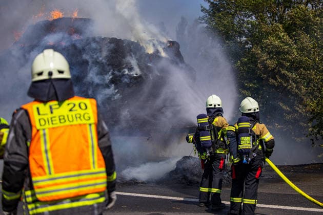 Strohballen fangen auf Anhänger Feuer Landwirt koppelt Traktor ab Flammen greifen auf Vegetation über Am 26.07.2026 geriet auf der L3114 zwischen Groß-Zimmern und Dieburg ein mit Strohquaderballen beladener Anhänger eines Traktors in Brand. Ein Landwirt koppelte nach Hinweisen von Autofahrern den Traktor ab und alarmierte die Feuerwehr, während der Brand auf die gesamte Ladung übergriff. Durch starken Wind breitete sich das Feuer zusätzlich auf einen Grünstreifen und angrenzende Vegetation aus, die Polizei sperrte die Landstraße. Die Feuerwehr Dieburg löschte den Brand mit Unterstützung der Feuerwehr Groß-Zimmern, laut Landwirt liegt eine natürliche Selbstentzündung nahe. Menschen wurden nicht verletzt. Dieburg L3114 H