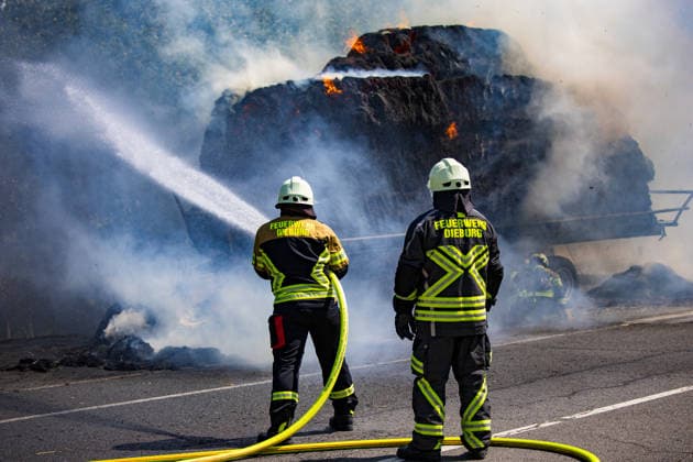 Strohballen fangen auf Anhänger Feuer Landwirt koppelt Traktor ab Flammen greifen auf Vegetation über Am 26.07.2026 geriet auf der L3114 zwischen Groß-Zimmern und Dieburg ein mit Strohquaderballen beladener Anhänger eines Traktors in Brand. Ein Landwirt koppelte nach Hinweisen von Autofahrern den Traktor ab und alarmierte die Feuerwehr, während der Brand auf die gesamte Ladung übergriff. Durch starken Wind breitete sich das Feuer zusätzlich auf einen Grünstreifen und angrenzende Vegetation aus, die Polizei sperrte die Landstraße. Die Feuerwehr Dieburg löschte den Brand mit Unterstützung der Feuerwehr Groß-Zimmern, laut Landwirt liegt eine natürliche Selbstentzündung nahe. Menschen wurden nicht verletzt. Dieburg L3114 H