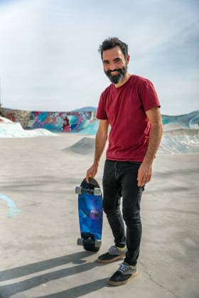 Man holding skateboard smiling in Taghazout skatepark in Morocco Imsouane, Souss-Massa, Morocco CR_UGOUSD260723-2074863-01 ,model released, Symbolfoto ,property released