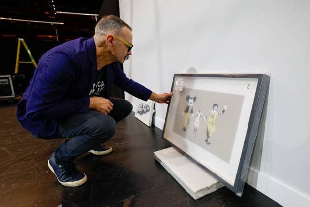 July 27, 2026, Tampa, Florida, USA: Richard Wormley, an assistant curator, examines an art piece by street artist, Banksy, at the Straz Center on Monday, July 27, 2026, in Tampa. Tampa USA - ZUMAs70_ 20260727_zan_s70_009 Copyright: xJeffereexWoox