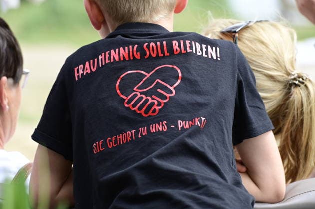 Ein Schüler trägt ein T-Shirt mit der Aufschrift: Frau Hennig soll bleiben. Sie gehört zu uns. Elternprotest - Grundschule Schöpstal droht Lehrerverlust. Große Unruhe zum Ferienbeginn an der Grundschule Schöpstal in Kunnersdorf: Einer langjährigen Klassenlehrerin droht im neuen Schuljahr die vollständige Abordnung an eine andere Schule. Da eine finale Entscheidung des Landesamtes für Schule und Bildung (LaSuB) noch aussteht, blicken viele Familien voller Ungewissheit auf die künftige Unterrichtsversorgung. Die Elternschaft wehrt sich nun massiv gegen den drohenden Unterrichtsausfall, den sie in der Vergangenheit bereits durch private Honorarkräfte im Sportunterricht abfedern musste. Mit einem offenen Brief an Ministerpräsident Copyright: xMatthiasxWehnertx