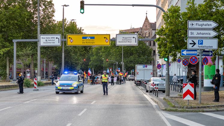 Montagsdemo Team Menschenrechte mit Gegendemonstration und Blockaden, Nürnberg, 27.07.2026 Ein Polizeifahrzeug mit Blaulicht führt einen Demonstrationszug am Plärrer an. Polizeikräfte sichern die Straße, während Teilnehmer mit Fahnen und Plakaten die Fahrbahn nutzen. Nürnberg Bayern Deutschland *** Monday Demonstration: Human Rights Team with a Counter-Demonstration and Roadblocks, Nuremberg, July 27, 2026 A police vehicle with its blue lights flashing leads a demonstration procession at the Plärrer. Police officers secure the street while participants carrying flags and signs march along the roadway. Nuremberg, Bavaria, Germany 20260727-286A3152-M4000
