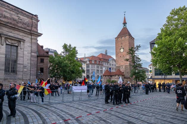 Montagsdemo Team Menschenrechte mit Gegendemonstration und Blockaden, Nürnberg, 27.07.2026 Abschlusskundgebung am Ende des Demozugs des Team Menschenrechte am Jakobsplatz. Polizeikräfte sichern den Platz mit Absperrgittern, Demonstranten stehen mit Fahnen und einem Transparent hinter den Absperrungen. Im Hintergrund ist der Weiße Turm zu erkennen. Nürnberg Bayern Deutschland *** Team Menschenrechte’s Monday Demonstration with a counter-demonstration and blockades, Nuremberg, July 27, 2026 Closing rally at the end of the Team Menschenrechte march at Jakobsplatz. Police secure the square with barricades; demonstrators stand behind the barricades with flags and a banner. The White Tower is visible in the background. Nuremberg, Bavaria, 20260727-286A3170-M4000