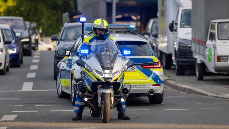 Montagsdemo Team Menschenrechte mit Gegendemonstration und Blockaden, Nürnberg, 27.07.2026 Ein Polizeimotorrad mit Blaulicht sichert eine Verkehrssperrung ab, im Hintergrund ein Streifenwagen mit aktiviertem Blaulicht. Der Polizeibeamte trägt Schutzkleidung mit Warnweste und Helm, umliegend stauen sich Fahrzeuge im Straßenverkehr. Nürnberg Bayern Deutschland *** Monday Demonstration: Human Rights Team with a counter-demonstration and roadblocks, Nuremberg, July 27, 2026 A police motorcycle with its blue lights flashing secures a roadblock; in the background, a patrol car with its blue lights flashing. The police officer is wearing protective gear, including a high-visibility vest and helmet, while traffic backs up around them. Nuremb 20260727-6V2A0136-M4000