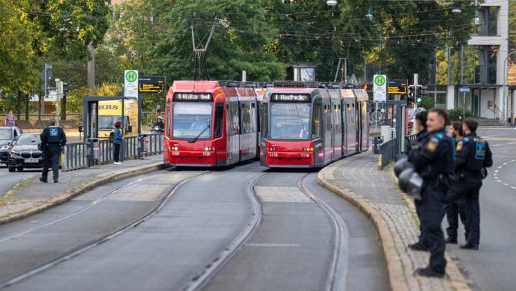 Montagsdemo Team Menschenrechte mit Gegendemonstration und Blockaden, Nürnberg, 27.07.2026 Zwei Straßenbahnen begegnen sich an einer Haltestelle, während am Straßenrand mehrere Polizeibeamte in Einsatzuniform postiert sind. Der öffentliche Nahverkehr läuft trotz erhöhter Polizeipräsenz im Rahmen einer Demonstration weiter. Nürnberg Bayern Deutschland *** Monday Demonstration by the Human Rights Team, featuring a counter-demonstration and blockades, Nuremberg, July 27, 2026 Two trams pass each other at a stop, while several police officers in riot gear are stationed at the curb. Public transit continues to operate despite an increased police presence during a demonstration. Nuremberg, Bavaria, Germany 20260727-6V2A0157-M4000