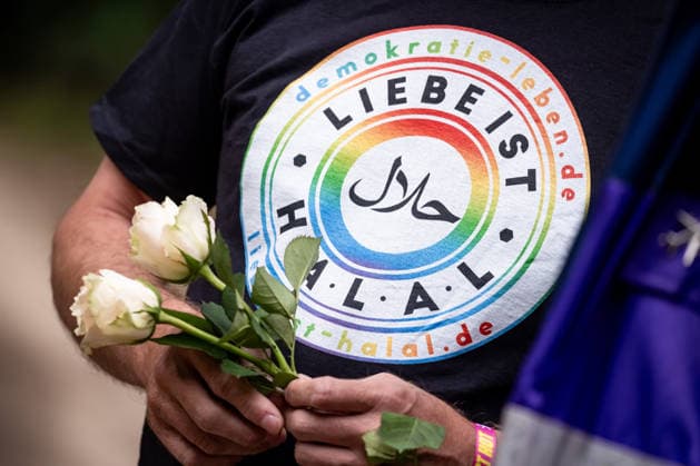 Ein Mann mit T-Shirt Liebe ist Halal und weissen Blumen gedenkt an den Opfer der Anschlag vom 25. Juli an den CSD im Tiergarten in Berlin am 27. Juli 2026. Der vermeintliche Attänteter Abdul B. soll mit einem LKW in dem Tiergarten gefahren und eine Frau getötet und weiter 29 Menschen verletzt haben. Gestern laut Polizei und LKA soll er während eine Operation in einer Gartenkolonie in Spandau aufgespürt und erschossen worden sein. Berliner gedenken an den Opfern der Attacke an den CSD *** A man wearing a T-shirt that reads Love is Halal and holding white flowers pays tribute to the victims of the July 25 attack at the CSD in Berlin’s Tiergarten on July 27, 2026. The alleged attacker, Abdul B, is said to have driven a truck through the Ti