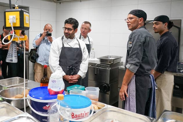 Hessens Wirtschaftsminister Kaweh Mansoori (SPD) und der Landrat des Kreis Groß-Gerau Thomas Will (SPD) bereiten in der Küche des AVM-Ausbildungsrestaurants Mangold in Bischofsheim ein Backhendl in Kürbiskern-Panade zu mit Küchenchef Florian Rothbauer - Bischofsheim 28.07.2026: Wirtschaftsminister Kaweh Mansoori besucht das Mangold *** Hesse’s Minister of Economic Affairs, Kaweh Mansoori (SPD), and Thomas Will (SPD), District Administrator of Groß Gerau, are preparing a fried chicken in a pumpkin seed breading in the kitchen of the AVM Mangold training restaurant in Bischofsheim with Head Chef Florian Rothbauer. Bischofsheim, July 28, 2026 Minister of Economic Affairs Kaweh Mansoori visits the Mangold