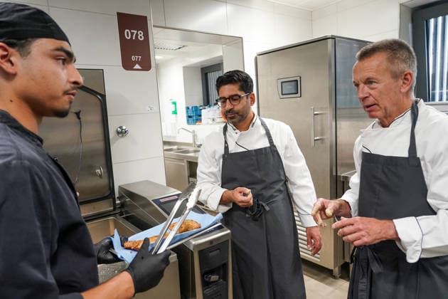 Hessens Wirtschaftsminister Kaweh Mansoori (SPD) und der Landrat des Kreis Groß-Gerau Thomas Will (SPD) bereiten in der Küche des AVM-Ausbildungsrestaurants Mangold in Bischofsheim ein Backhendl in Kürbiskern-Panade zu mit dem Auszubildenden Salman Guhaish - Bischofsheim 28.07.2026: Wirtschaftsminister Kaweh Mansoori besucht das Mangold *** Hesse’s Minister of Economic Affairs, Kaweh Mansoori (SPD), and Thomas Will (SPD), District Administrator of Groß Gerau, are preparing a fried chicken coated in pumpkin seed breading in the kitchen of the AVM Mangold training restaurant in Bischofsheim, together with trainee Salman Guhaish. Bischofsheim, July 28 July 2026 Minister of Economic Affairs Kaweh Mansoori visits the Mangold