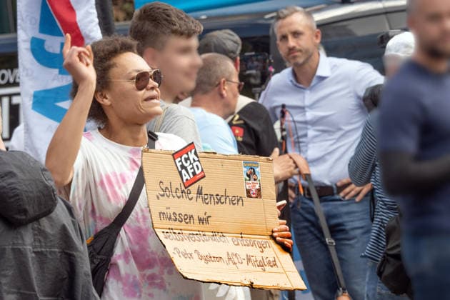 Gegendemonstrantin bei AfD-Wahlkampf mit Ulrich Siegmund, AfD Spitzenkandidat in Sachsen-Anhalt, AfD-Infostand in Magdeburg, 28. Juli 2026 Deutschland, Magdeburg, 28. Juli 2026, Gegendemonstrantin bei AfD Wahlkampf in der Magdeburger Innenstadt, mit Anti-AfD-Plakat, im Hinterund rechts Ulrich Siegmund, AfD-WSpitzenkandidat bei den Landtagswahlen in Sachsen-Anhalt am 6. September, Wahlkampfstand an der Ecke Goldschmiedebrücke - Breiter Weg, viele Wähler kommen, um ein Slfie mit dem Spitzenkandidaten zu machen, rechtsextreme Landespartei, Politiker, Politik, *** Counter-protester at an AfD campaign event with Ulrich Siegmund, the AfD’s top candidate in Saxony-Anhalt, AfD information booth in Magdeburg, July 28, 2026; Germany, Magdeburg, Jul