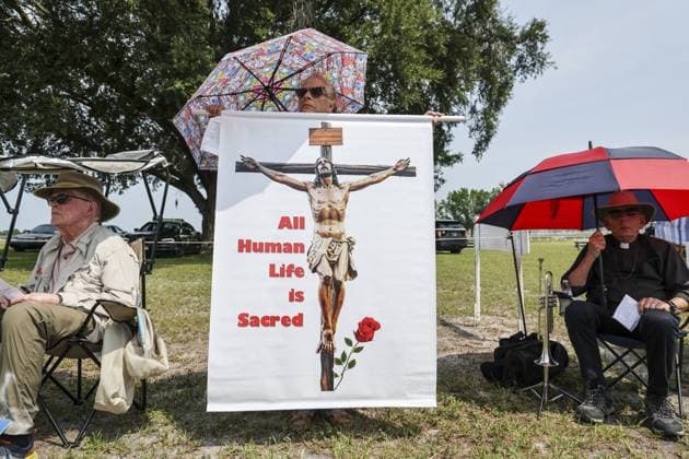 July 28, 2026, Raiford, Florida, USA: Angela Stemberger, of Daytona Beach, displays an image of a crucifix during a protest near the Florida State Prison on the day of the scheduled execution of James Duckett on Tuesday, July 28, 2026, in Raiford. Raiford USA - ZUMAs70_ 20260728_zan_s70_019 Copyright: xDouglasxR.xCliffordx