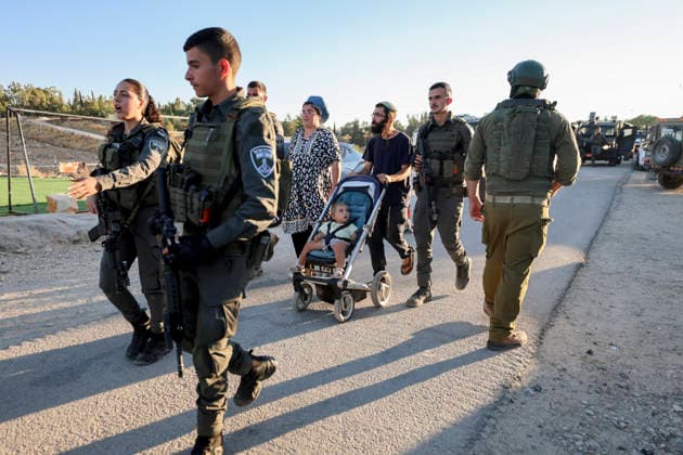 Hebron West Bank Umm Al Khair Memorial Israeli security personnel walk beside civilians, including a man pushing a child in a stroller, near the memorial ceremony site in the village of Umm al-Khair, in Masafer Yatta, south of Hebron in the occupied West Bank, on July 28, 2026. Al-Hathaleen was killed on July 28, 2025, during a confrontation involving Israeli settlers in Umm al-Khair, and local witnesses said Israeli forces assaulted Israeli Knesset member Ofer Cassif during the anniversary incident. Hebron West Bank Palestinian Territories Copyright: xMosabxShawerx