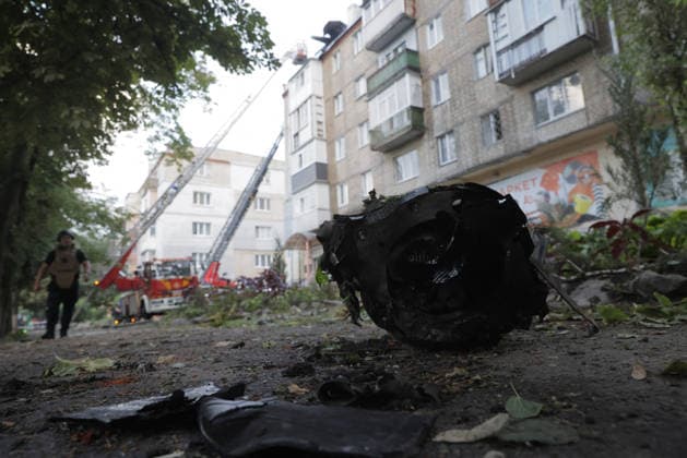 Shahed Drone Strike - Kharkiv A charred engine fragment from a russian Shahed drone lies in the yard of a five-storey residential building in the Novobavarski district of Kharkiv, Ukraine, on July 28, 2026, as a fire truck with an extended aerial ladder works to extinguish a roof fire on the building behind, and an emergency responder in body armor walks through the debris-strewn scene; fallen branches and scorched metal fragments are scattered across the ground, after all residents were evacuated and two people were reported injured following the strike, with emergency services continuing to work at the site. Photo by Titov Yevhen ABACAPRESS.COM Kharkiv Kharkiv Oblast Ukraine  Copyright: xTitovxYevhen ABACAx