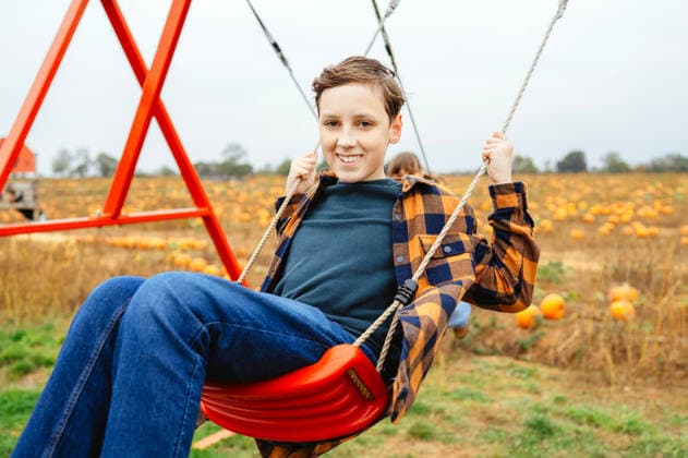 Teen boy enjoying a swing beside a pumpkin patch in autumn Moulton, England, United Kingdom CR_JNDO260727-2088041-01 ,model released, Symbolfoto ,property released