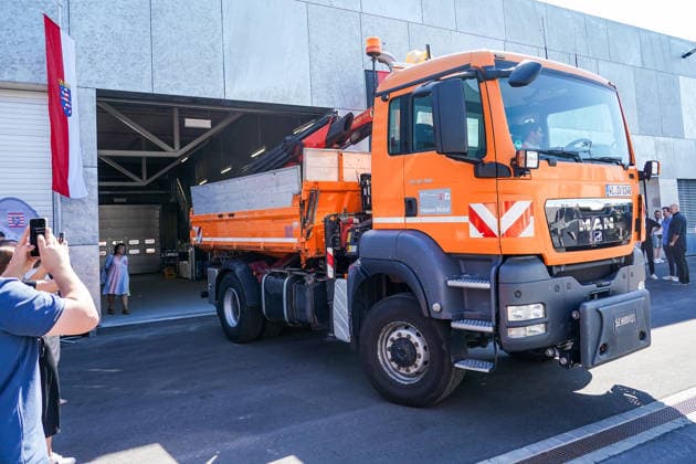 Wirtschafts- und Verkehrsminister Kaweh Mansoori (SPD) am Steuer des Arbeitsfahrzeuges bei der Einweihung der neuen Straßenmeisterei in Groß-Gerau, das er symbolisch zur Einweihung aus der neuen Fahrzeughalle fährt - Gross-Gerau 29.07.2026: Wirtschafts- und Verkehrsminister Kaweh Mansoori besucht neue Straßenmeisterei *** Kaweh Mansoori, SPD Minister of Economic Affairs and Transportation, at the wheel of the work vehicle during the inauguration of the new road maintenance depot in Groß Gerau, which he symbolically drives out of the new vehicle hangar for the inauguration. Groß Gerau, July 29, 2026: Minister of Economic Affairs and Transportation Kaweh Mansoori visits the new road maintenance depot