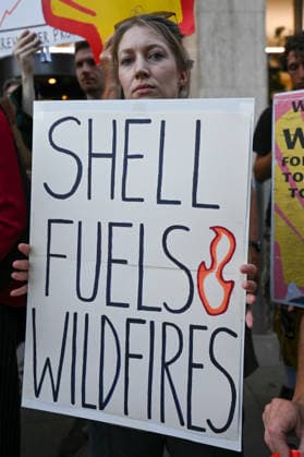 Fossil Free London Protest in UK - 29 Jul 2026 A member of the campaign group Fossil Free London holds a placard during a demonstration outside Shell s headquarters in London to highlight the role of fossil fuel production in climate change and its contribution to the increasing risk of wildfires across Europe. Campaigners from Fossil Free London staged a protest outside Shell Centre, Shell’s headquarters in London. During the demonstration, one participant dressed as a firefighter was covered in a black liquid resembling oil. Behind them, a banner read World on Fire, while placards displayed the messages Shell Fuels Wildfires and Oil Fuels Wildfires . London United Kingdom Copyright: xJamesxWilloughbyx xSOPAxImagesx JWILLOUGHBY_3098