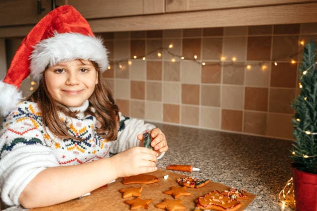 Smiling child girl wearing Santa hat while decorating cookies Corby, England, United Kingdom R_JNDO260715-2076316-01 ,model released, Symbolfoto ,property released