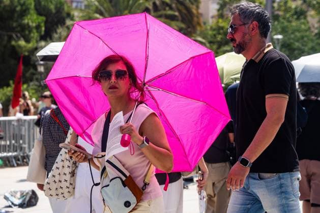 July 29, 2026, Barcelona, ES: BARCELONA, SPAIN - JULY 29, 2026. A woman walks with an umbrella to shield herself from the sun near the Sagrada Familia on the first day of the summer s fourth heatwave in Spain. Local authorities have issued high-temperature alerts across Catalonia, urging residents and visitors to take precautions against extreme heat expected to last throughout the week. Barcelona ES  - ZUMAq101 20260729_zna_q101_094 Copyright: xMarcxAsensioxClupesx