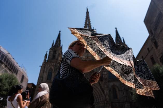 July 29, 2026, Barcelona, ES: BARCELONA, SPAIN - JULY 29, 2026. A woman prepares to open her umbrella to shield herself from the sun in Barcelona s Cathedral Square, on the first day of the summer s fourth heatwave in Spain. Local authorities have issued high-temperature alerts across Catalonia, urging residents and visitors to take precautions against extreme heat expected to last throughout the week. Barcelona ES  - ZUMAq101 20260729_zna_q101_100 Copyright: xMarcxAsensioxClupesx