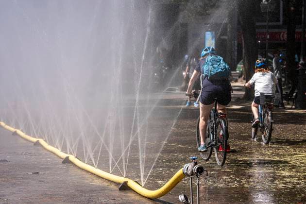 Cooling Cologne, Aktion der Stadt Köln zur Abkühlung von Hitzebelasteten Plätzen, hier der Rudolfplatz in der Innenstadt, bei knapp 37Â°C an dem Tag, ein Sprühschlauch verspritzt feine Wassertröpfen, die die unmittelbare Umgebung einige Grade abkühlt, eine Aktion die bei extremer Hitzebelastung vorgenommen wird, zur Anpassung des Stadtklimas an den Klimawandel, Passanten genießen den kühlenden Moment, dazu gibts Tipps zum Umgang mit Extremhitze, NRW, Deutschland, Extremhitze *** Cooling Cologne, a City of Cologne initiative to cool down areas affected by heat, here at Rudolfplatz in the city center, with temperatures nearing 37°C that day, a spray hose disperses fine droplets of water that cool the immediate surroundings by a few de