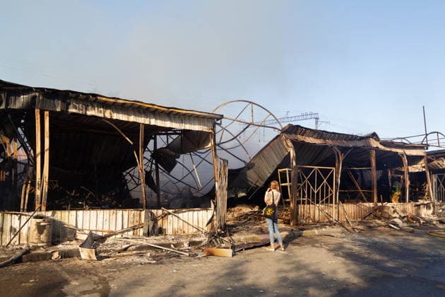 A woman faces the charred stalls of the Antykar market in Obolonskyi district, which caught fire following an overnight Russian missile strike, Kyiv, Ukraine, July 30, 2026. Debris fell on the market near the Pochaina metro station, igniting trading pavilions. The blaze covered an area of about 100 square metres. Traders’ goods were destroyed, leaving only burnt-out metal structures at the site. (Photo by Kyrylo Chubotin Ukrinform) Market in Kyiv catches fire due to overnight Russian attack  Copyright: xKyryloxChubotinx