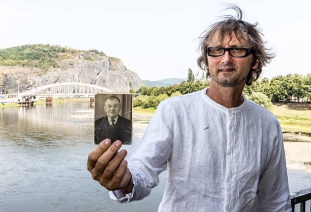 Czech senator and historian Martin Krsek holds a photograph of his great-great-grandfather, who was also thrown from the bridge (in the background) into the river, during the memorial event to commemorate 1945 Usti nad Labem massacre of Sudeten Germans following the end of World War II in Usti nad Labem, Czech Republic, on July 31, 2026. His great-great-grandfather survived and was subsequently displaced. He sent the photograph from abroad as a postcard. (CTKxPhoto VojtechxHajek) CTKPhotoP2026073106063  CTKPhotoP2026073106063