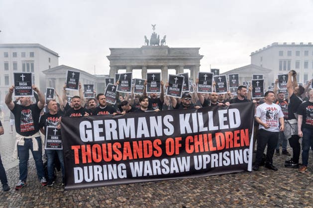 82. Jahrestag des Warschauer Aufstands, spektakuläre Protestaktion von polnischen Aktivisten, sie erinnern an die Tausenden Kinder, die die deutschen Besatzer beim Warschauer Aufstand 1944 ermordet haben, Berlin, 1. August 2026 Deutschland, Berlin, 1. August 2026, spektakuläre Protestaktion von polnischen Aktivisten, sie erinnern an die Tausenden Kinder, die die deutschen Besatzer beim Warschauer Aufstand 1944 ermordet haben, kurz zuvor hatten die Demonstranten rote Bengalos vor dem Brandenburger Tor gezündet, die die ganze Szene in starken Rauch einhüllten, Demonstranten halten Schilder mit den Namen der ermordeten Kinder hoch, Samstag um 14:15 Uhr, die Protestaktion dauerte nur 5 Minuten, Aktion zum 82. Jahrestag des Warschauer Aufsta