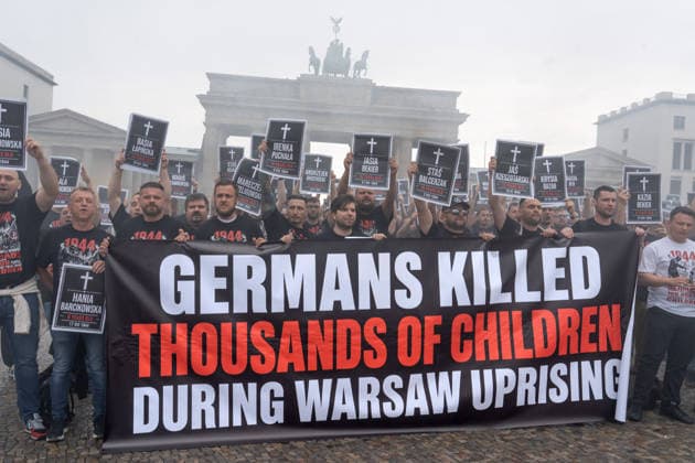 82. Jahrestag des Warschauer Aufstands, spektakuläre Protestaktion von polnischen Aktivisten, sie erinnern an die Tausenden Kinder, die die deutschen Besatzer beim Warschauer Aufstand 1944 ermordet haben, Berlin, 1. August 2026 Deutschland, Berlin, 1. August 2026, spektakuläre Protestaktion von polnischen Aktivisten, sie erinnern an die Tausenden Kinder, die die deutschen Besatzer beim Warschauer Aufstand 1944 ermordet haben, kurz zuvor hatten die Demonstranten rote Bengalos vor dem Brandenburger Tor gezündet, die die ganze Szene in starken Rauch einhüllten, Demonstranten halten Schilder mit den Namen der ermordeten Kinder hoch, Samstag um 14:15 Uhr, die Protestaktion dauerte nur 5 Minuten, Aktion zum 82. Jahrestag des Warschauer Aufsta