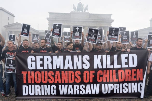 82. Jahrestag des Warschauer Aufstands, spektakuläre Protestaktion von polnischen Aktivisten, sie erinnern an die Tausenden Kinder, die die deutschen Besatzer beim Warschauer Aufstand 1944 ermordet haben, Brandenburger Tor, Berlin, 1. August 2026 Deutschland, Berlin, 1. August 2026, spektakuläre Protestaktion von polnischen Aktivisten, sie erinnern an die Tausenden Kinder, die die deutschen Besatzer beim Warschauer Aufstand 1944 ermordet haben, kurz zuvor hatten die Demonstranten rote Bengalos vor dem Brandenburger Tor gezündet, die die ganze Szene in starken Rauch einhüllten, Demonstranten halten Schilder mit den Namen der ermordeten Kinder hoch, Samstag um 14:15 Uhr, die Protestaktion dauerte nur 5 Minuten, Aktion zum 82. Jahrestag de