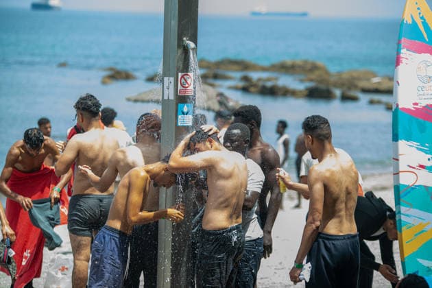 August 1, 2026, Ceuta, Ceuta, Spain: A group of migrants use beach showers near the Temporary Stay Centre for Immigrants Ceuta Spain - ZUMAd308 20260801_zsp_d308_086 Copyright: xJuanxCarlosxLucasx