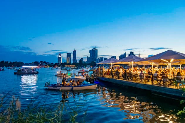 Lichterlfest (Lichterfest, Festival of Lights) at oxbow lake Alte Donau (Old Danube), illuminated boats, high-rises of Donaucity, floating restaurant Strandcafe Vienna 22. Donaustadt Wien Austria