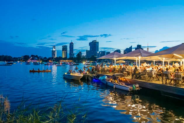 Lichterlfest (Lichterfest, Festival of Lights) at oxbow lake Alte Donau (Old Danube), illuminated boats, high-rises of Donaucity, floating restaurant Strandcafe Vienna 22. Donaustadt Wien Austria