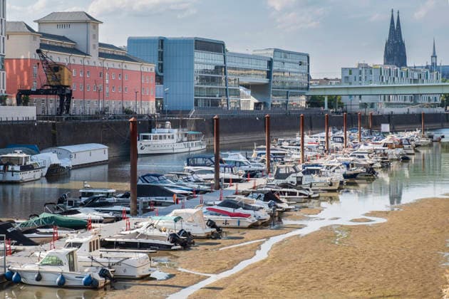 News Bilder des Tages Blick auf die Marina im Kölner Rheinauhafen bei extremem Niedrigwasser des Rheins im August 2026. Der schlammige Hafenboden liegt weitflächig trocken, und zahlreiche Motorboote, Yachten und Sportboote liegen im Hafenbecken auf Grund. Im Hintergrund ist das historische Malzkasten-Gebäude, moderne Büroarchitektur und die Silhouette des Kölner Doms bei leicht bewölktem Sommerhimmel zu sehen. Das Motiv dient als Symbolbild für Klimawandel, extreme Sommerhitze, Dürre und die Auswirkungen auf Binnengewässer und Freizeitschifffahrt in Nordrhein-Westfalen. *** View of the marina in Cologne s Rhineauhafen during extreme low water levels of the River Rhine in August 2026. The muddy harbor bed lies dry over a wide area, causing numerous motor 20260802-DSCF0138