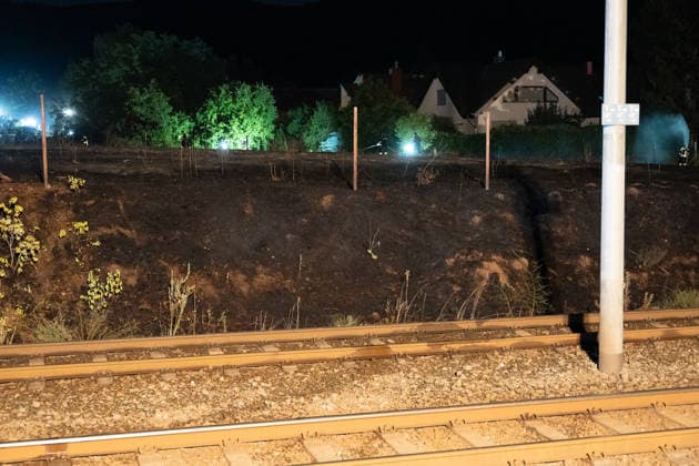 Großer Flächenbrand bedroht Wohngebiet Am 03.08.2026 gegen 02:00 Uhr brannten zwischen Seeheim-Jugenheim und Alsbach im Landkreis Darmstadt-Dieburg rund 28.000 Quadratmeter Feld und Gestrüpp entlang der L3100. Die Feuerwehr stoppte die Flammen etwa fünf Meter vor angrenzenden Wohnhäusern. Ein Anwohner erlitt beim eigenständigen Löschversuch eine Rauchgasvergiftung und wurde vom Rettungsdienst in ein Krankenhaus gebracht. Die Straßenbahnstrecke zwischen Alsbach und Seeheim-Jugenheim wurde gesperrt, ein Schienenersatzverkehr eingerichtet. Zur Brandbekämpfung kam eine Drohne mit Wärmebildkamera zum Aufspüren von Glutnestern zum Einsatz. Seeheim-Jugenheim Hessen Deutschland *** Large Wildfire Threatens Residential Area On August 3,