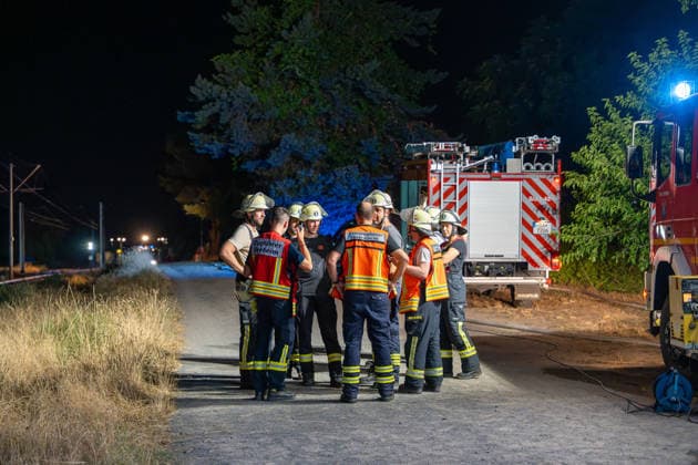 Großer Flächenbrand bedroht Wohngebiet Am 03.08.2026 gegen 02:00 Uhr brannten zwischen Seeheim-Jugenheim und Alsbach im Landkreis Darmstadt-Dieburg rund 28.000 Quadratmeter Feld und Gestrüpp entlang der L3100. Die Feuerwehr stoppte die Flammen etwa fünf Meter vor angrenzenden Wohnhäusern. Ein Anwohner erlitt beim eigenständigen Löschversuch eine Rauchgasvergiftung und wurde vom Rettungsdienst in ein Krankenhaus gebracht. Die Straßenbahnstrecke zwischen Alsbach und Seeheim-Jugenheim wurde gesperrt, ein Schienenersatzverkehr eingerichtet. Zur Brandbekämpfung kam eine Drohne mit Wärmebildkamera zum Aufspüren von Glutnestern zum Einsatz. Seeheim-Jugenheim Hessen Deutschland *** Large Wildfire Threatens Residential Area On August 3,