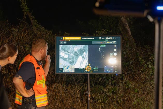 Großer Flächenbrand bedroht Wohngebiet Am 03.08.2026 gegen 02:00 Uhr brannten zwischen Seeheim-Jugenheim und Alsbach im Landkreis Darmstadt-Dieburg rund 28.000 Quadratmeter Feld und Gestrüpp entlang der L3100. Die Feuerwehr stoppte die Flammen etwa fünf Meter vor angrenzenden Wohnhäusern. Ein Anwohner erlitt beim eigenständigen Löschversuch eine Rauchgasvergiftung und wurde vom Rettungsdienst in ein Krankenhaus gebracht. Die Straßenbahnstrecke zwischen Alsbach und Seeheim-Jugenheim wurde gesperrt, ein Schienenersatzverkehr eingerichtet. Zur Brandbekämpfung kam eine Drohne mit Wärmebildkamera zum Aufspüren von Glutnestern zum Einsatz. Seeheim-Jugenheim Hessen Deutschland *** Large Wildfire Threatens Residential Area On August 3,