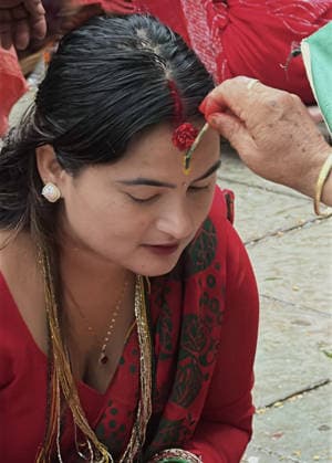 August 3, 2026, Kathmandu, Nepal: A woman puts tika on her forehead as a blessings after offering prayers during Shrawan Somvar at a Shiva temple in Kathmandu, Nepal on August 3, 2026. Mondays (Somvars) in the sacred month of Shrawan are considered especially auspicious for the worship of Lord Shiva. Devotees observe fasts and offer prayers seeking blessings, health, and prosperity. Many women keep the Shrawan Somvar fast for the long life and well-being of their husbands, while unmarried women pray for a virtuous and compatible life partner. Kathmandu Nepal  - ZUMAs233 20260803_zap_s233_005 Copyright: xSunilxSharmax