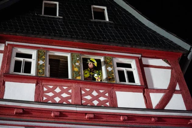 Feuer im Dachgeschoss eines Fachwerkhauses Flammen schlagen aus dem Fenster Feuerwehr riegelt enge Altstadt ab Am 03.08.2026 brannte gegen 21:00 Uhr ein Fachwerkhaus in der Oberstadt 18 in der Altstadt von Lich. Der Brand betraf das Obergeschoss und den Dachbereich des Gebäudes, es kam zu starker Rauchentwicklung und Flammenaustritt. Beim Eintreffen der Feuerwehr befand sich niemand mehr im Gebäude. Die Freiwillige Feuerwehr Lich leitete Außen- und Innenangriff ein und baute wegen der engen Altstadtbebauung eine Riegelstellung mit der Drehleiter zum Schutz der Nachbarhäuser auf. Lich Hessen Deutschland *** Fire in the attic of a half-timbered house; flames are shooting out of the window; firefighters cordon off the narrow old t