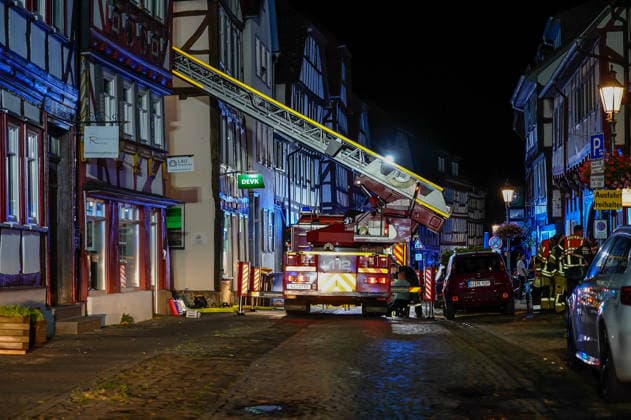 Feuer im Dachgeschoss eines Fachwerkhauses Flammen schlagen aus dem Fenster Feuerwehr riegelt enge Altstadt ab Am 03.08.2026 brannte gegen 21:00 Uhr ein Fachwerkhaus in der Oberstadt 18 in der Altstadt von Lich. Der Brand betraf das Obergeschoss und den Dachbereich des Gebäudes, es kam zu starker Rauchentwicklung und Flammenaustritt. Beim Eintreffen der Feuerwehr befand sich niemand mehr im Gebäude. Die Freiwillige Feuerwehr Lich leitete Außen- und Innenangriff ein und baute wegen der engen Altstadtbebauung eine Riegelstellung mit der Drehleiter zum Schutz der Nachbarhäuser auf. Lich Hessen Deutschland *** Fire in the attic of a half-timbered house; flames are shooting out of the window; firefighters cordon off the narrow old t