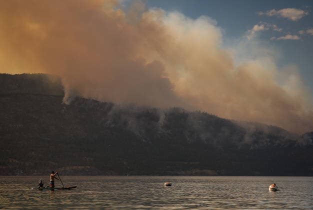 August 3, 2026, Lake Country, Bc, CANADA: A man paddles a paddleboard on Okanagan Lake, in Lake Country, B.C., as the Quilpituk Creek wildfire burns on the mountainside across the lake, near Fintry, on Monday, Aug. 3, 2026. Lake Country CANADA  - ZUMAc35_ 20260803_zaf_c35_059 Copyright: xDarrylxDyckx