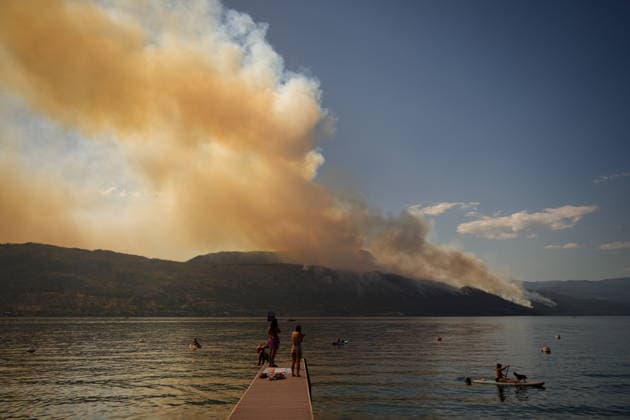 August 3, 2026, Lake Country, Bc, CANADA: People stand on a dock while a woman paddles a paddleboard on Okanagan Lake, in Lake Country, B.C., as the Quilpituk Creek wildfire burns on the mountainside across the lake near Fintry, on Monday, Aug. 3, 2026. Lake Country CANADA  - ZUMAc35_ 20260803_zaf_c35_068 Copyright: xDarrylxDyckx