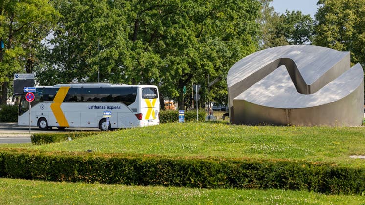Flughafen Nürnberg, 04.08.2026 Ein Reisebus der Lufthansa Express fährt an einer markanten Metalllogo auf einem Kreisverkehr am Eingang des Flughafengeländes vorbei. Im Hintergrund ist ein Hinweisschild zum Flughafen zu erkennen. Nürnberg Flughafen Bayern Deutschland *** Nuremberg Airport, August 4, 2026 A Lufthansa Express tour bus passes by a distinctive metal logo at a roundabout at the entrance to the airport grounds. In the background, a sign pointing to the airport can be seen. Nuremberg Airport, Bavaria, Germany 20260804-1V9A6673-M4000