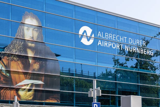 Flughafen Nürnberg, 04.08.2026 Fassade des Albrecht Dürer Airport Nürnberg mit großformatigem Selbstbildnis von Albrecht Dürer und Logo des Flughafens. Die Glasfassade des Terminalgebäudes spiegelt den blauen Himmel. Nürnberg Flughafen Bayern Deutschland *** Nuremberg Airport, August 4, 2026: The facade of the Albrecht Dürer Airport Nuremberg featuring a large-scale self-portrait by Albrecht Dürer and the airport’s logo. The glass facade of the terminal building reflects the blue sky. Nuremberg Airport, Bavaria, Germany 20260804-1V9A6684-M4000