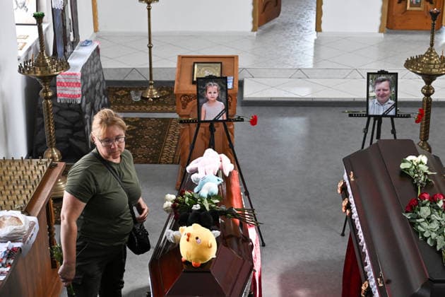 A woman with a bouquet stands by a coffin during a funeral service for members of the Voronov family, killed when a Russian Iskander-M ballistic missile directly struck their home on the night of Thursday, July 30, Radushne settlement, Kryvyi Rih district, Dnipropetrovsk region, Ukraine, August 3, 2026. Five family members whose identities have been officially confirmed were laid to rest: parents Artem, 47, and Olena, 41, together with their children Mark, 17, Azarii Ilai, 11, and Emiliia, 6. Five other children who were in the house that night - Zakhar, Dominika, Viorika, Federika and one-and-a-half-year-old grandson Artem - are still officially listed as missing. Rescuers recovered 17 body fragments from the rubble, and complex forensic D  Copyright: xDmytroxSmolienkox